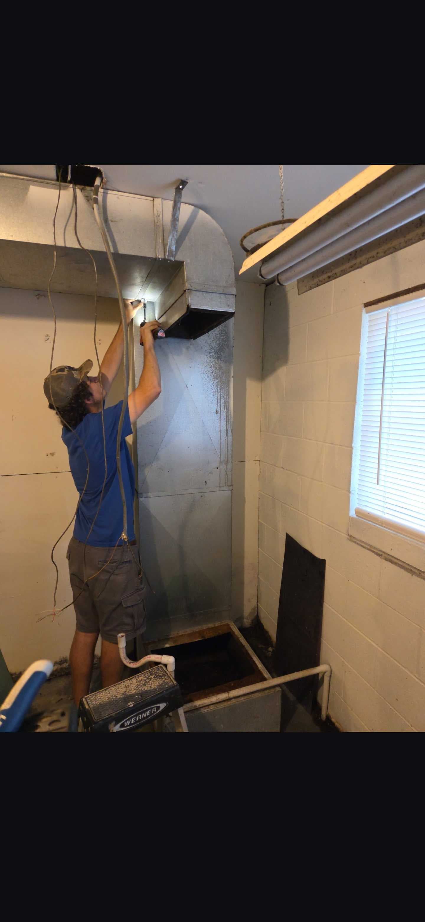 A technician working on the overhead duct connection.